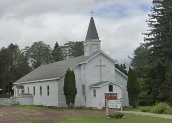 A white building with large cross and steeple.